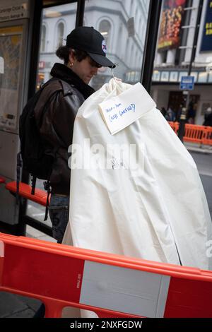 Un uomo in possesso di un capo di abbigliamento coperto si trova presso una fermata dell'autobus nel West End della capitale, il 28th febbraio 2023, a Londra, in Inghilterra. Foto Stock