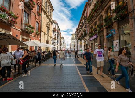 Una vivace scena di strada a Leon sul cammino di Santiago in Spagna, con persone che camminano davanti a negozi e ristoranti affascinanti Foto Stock