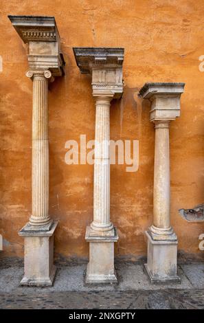 Tre antiche colonne si ergono contro un muro d'oro al Museo Biblico e Orientale di León, Spagna Foto Stock