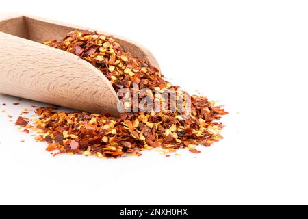 La pila di un peperoncino rosso tritato, peperoncino essiccato in scaglie e semi isolato su sfondo bianco in un convogliatore Foto Stock