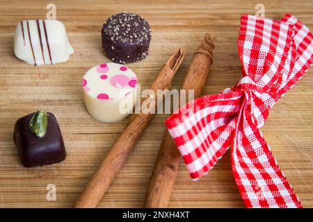 Confezione di tartufi di cioccolato Holiday. Mini praline decorate con bastoncini di cannella e nastro rosso e bianco. Foto Stock