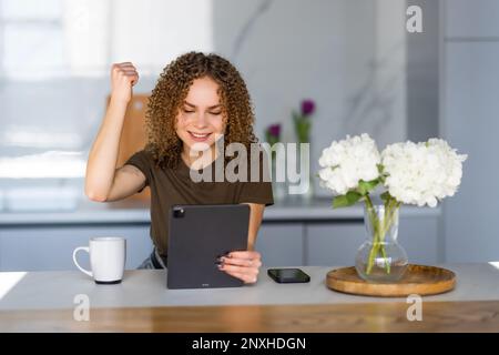 Donna emotiva che partecipa all'asta online utilizzando il tablet a casa Foto Stock