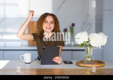 Donna emotiva che partecipa all'asta online utilizzando il tablet a casa Foto Stock