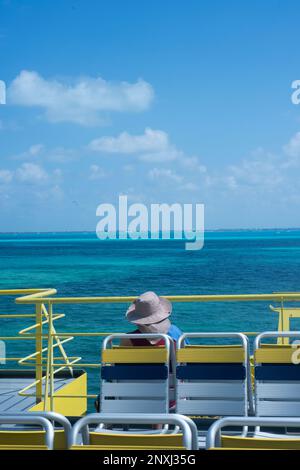 Il passeggero seduto su un ponte scoperto di una nave osserva il Mar dei Caraibi in una giornata di sole in Messico Foto Stock