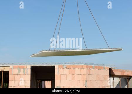 La lastra di pavimento prefabbricata vola attraverso l'aria di fronte bue cielo Foto Stock