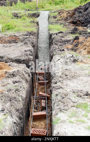 Riempimento della fondazione della striscia con cemento in cantiere. inizio della costruzione di una casa. Foto Stock