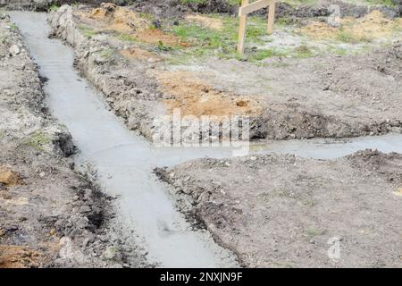 Riempimento della fondazione della striscia con cemento in cantiere. inizio della costruzione di una casa. Foto Stock