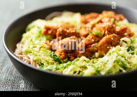 Ricci di soia piccanti su cavolo sminuzzato di savoia, serviti con spaghetti di grano saraceno. Foto Stock