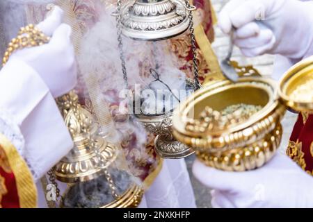 Dettaglio della mano di un ragazzo altare o di un'accolita in una processione della settimana Santa che riempie di incenso uno dei censori Foto Stock