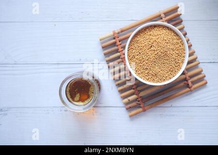 olio di senape e semi in un contenitore su tavola Foto Stock