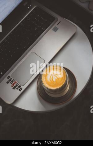 Latte di caffè con computer portatile in un tavolo rotondo bianco Foto Stock