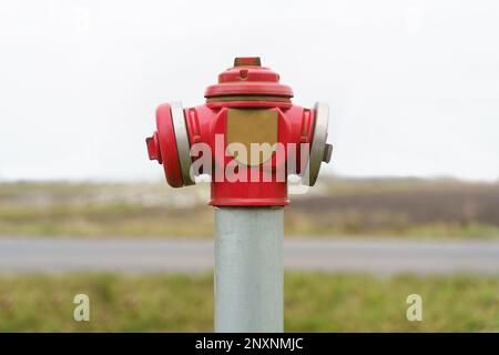 Accanto alla strada si trova un idrante rosso brillante. Foto Stock