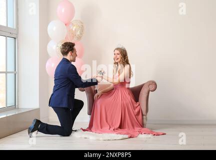 Ragazzo adolescente che legava il corsage intorno al polso della sua ragazza per un Prom in camera Foto Stock