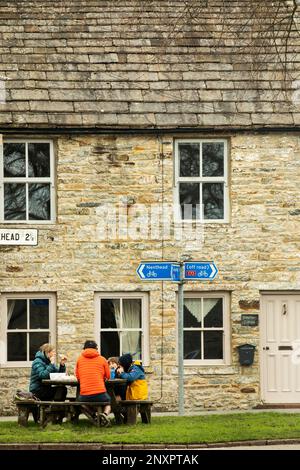 Picnic con la famiglia nel verde del villaggio fuori Rosemary Cottage, vicino a un cartello per Nenthead e in bicicletta fuori strada a Garrigill, Cumbria Foto Stock