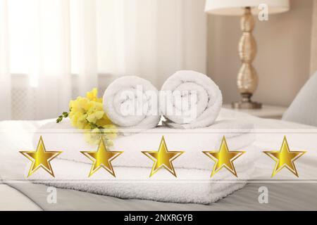 Asciugamani freschi e bianchi con fiori sul letto in una camera d'albergo a cinque stelle Foto Stock