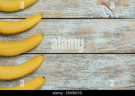 Banane gialle mature su tavolo di legno chiaro, piatto. Spazio per il testo Foto Stock