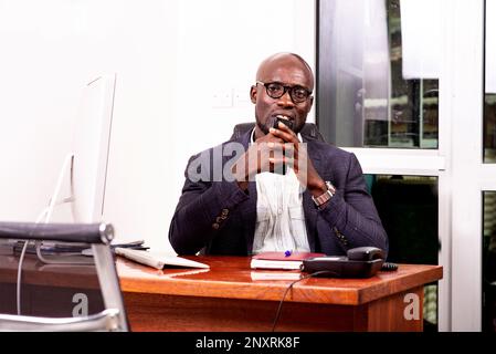 ritratto di un uomo d'affari adulto sicuro che tiene il telefono cellulare in ufficio. Foto Stock