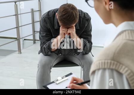 Psicoterapeuta che lavora con un giovane tossicodipendente al chiuso Foto Stock