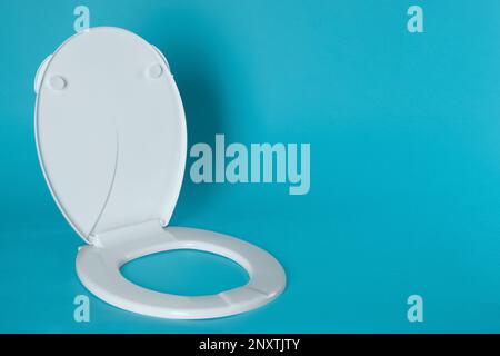 Nuovo sedile in plastica per gabinetto su sfondo azzurro, spazio per testo Foto Stock