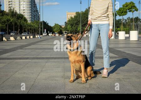 Donna con il suo cane aggressivo sulla strada della città, primo piano Foto Stock