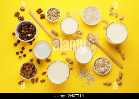 Diversi latte vegano e ingredienti su sfondo giallo, piatto Foto Stock