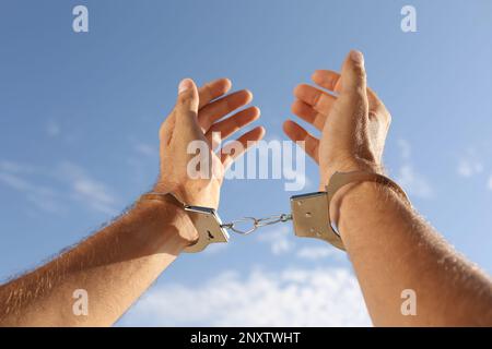 Uomo in manette contro il cielo blu all'aperto, primo piano Foto Stock