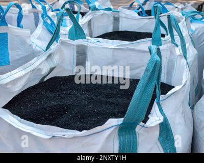 Granuli di polistirene nero in sacchetti grandi con manici, messa a fuoco selettiva. Materiale di costruzione e riparazione Foto Stock