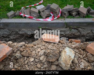 Marciapiede rotto. Conduzione del cavo interrato. Posa dei cavi. Comunicazioni in città. Mattoni di pavimentazione scavati. Ristrutturazione dell'area pedonale Foto Stock