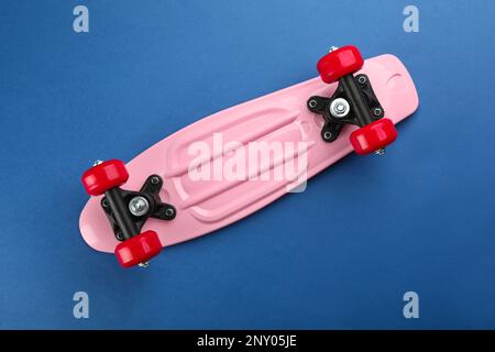 Skateboard rosa su sfondo blu, vista dall'alto Foto Stock