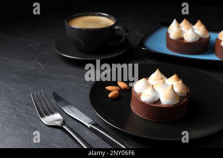 Deliziosa crostata di cioccolato al caramello salato con meringa e mandorle su tavola nera Foto Stock