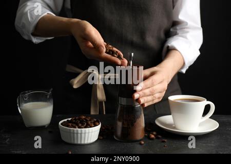 Donna che usa il macinacaffè manuale al tavolo nero, primo piano Foto Stock