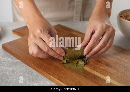 Donna che prepara foglie d'uva farcite a tavola, primo piano Foto Stock