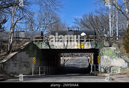 EMPORIA, KANSAS - 1 MARZO 2023 Burlington Northern Santa Fe (BNSF) treno che trasporta una serie di carri armati riempiti con le teste di sciroppo di mais ad est al cavalcavia della strada del Congresso che ha bisogno di riparazione di infrastruttura come le pareti di cemento stanno fallendo. Foto Stock