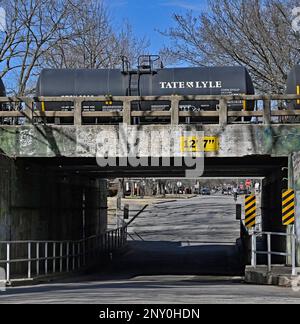 EMPORIA, KANSAS - 1 MARZO 2023 Burlington Northern Santa Fe (BNSF) treno che trasporta una serie di carri armati riempiti con le teste di sciroppo di mais ad est al cavalcavia della strada del Congresso che ha bisogno di riparazione di infrastruttura come le pareti di cemento stanno fallendo. Foto Stock