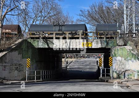 EMPORIA, KANSAS - 1 MARZO 2023 Burlington Northern Santa Fe (BNSF) treno che trasporta una serie di carri armati riempiti con le teste di sciroppo di mais ad est al cavalcavia della strada del Congresso che ha bisogno di riparazione di infrastruttura come le pareti di cemento stanno fallendo. Foto Stock