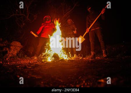 Nablus, Palestina. 01st Mar, 2023. I palestinesi mascherati che trasportano bastoni di legno intorno al fuoco stanno in guardia durante la notte per difendersi dagli attacchi dei coloni ebrei, a sud di Nablus in Cisgiordania. Gli attacchi dei coloni sono aumentati contro i palestinesi, in particolare i villaggi a sud di Nablus, come Hawara Burin, l'ultimo dei quali è stato sulla città di Hawara, il cui danno è stato causato dall'incendio di decine di case e negozi e più di un centinaio di automobili. Il primo ministro palestinese Muhammad Shtayyeh ha affermato che le perdite totali sono state stimate a circa $5 milioni di dollari. Credit: SOPA Images Limited/Alamy Live News Foto Stock