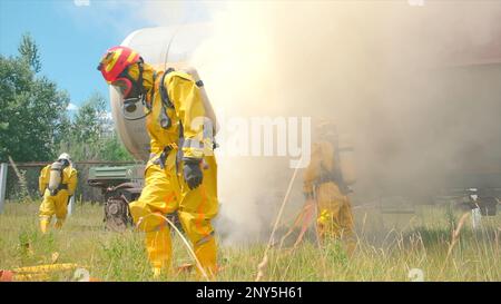 Vigili del fuoco e treno in fiamme. Fermo. I vigili del fuoco si stanno preparando con attrezzature per spegnere gli incendi. Predisposizione per lo spegnimento di un vagone ferroviario industriale Foto Stock