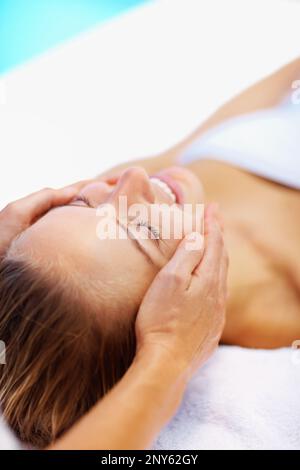 Donna sorridente godendo un massaggio pacifico del viso. Giovane donna che si coccole al centro termale , una massaggiatrice che le dona un massaggio viso. Foto Stock
