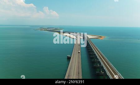 Vista dall'alto del bellissimo ponte sul mare blu. Scatto. Lunga autostrada con ponte sull'acqua blu. Ponte attraverso stretto tra le isole con bella stagione Foto Stock