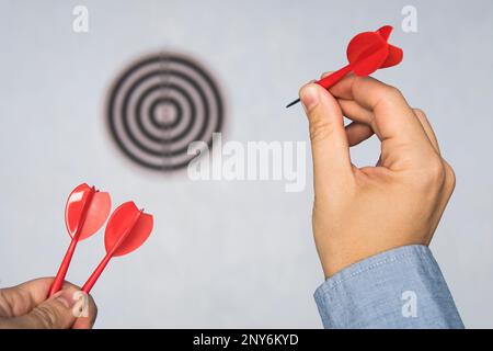 Imprenditore tenendo un dart mirando all'obiettivo - business targeting, mira, la nozione di messa a fuoco. L Uomo in camicia blu giocare a freccette. colpire il bersaglio. Successo Foto Stock