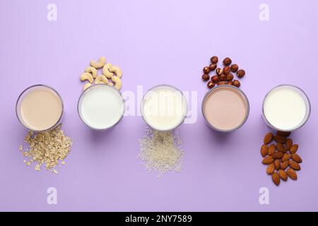 Diversi latte vegano e ingredienti su sfondo violetto, piatto Foto Stock