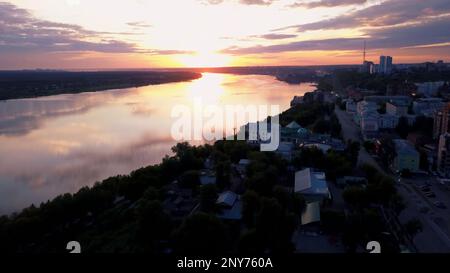 Volare sopra la città e un tempio con cupola dorata situato sul fiume. Fermo. La bellezza della piccola città estiva in serata Foto Stock