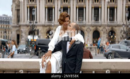 Coppia amorevole che scatta il video il loro giorno di nozze. Azione. Sposa in abito bianco e sposo in abito sullo sfondo dell'architettura della grande città Foto Stock