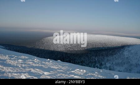 Paesaggio calmo e freddo con l'infinita valle di foresta ghiacciata. Fermo. Veduta aerea di una montagna innevata Foto Stock