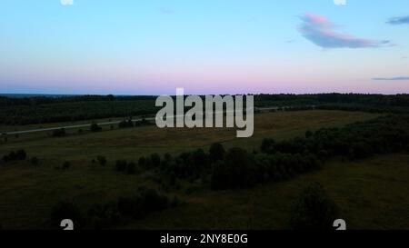 Vista aerea e tramonto sul prato. Fermo. Splendidi campi verdi e calda luce solare al tramonto Foto Stock