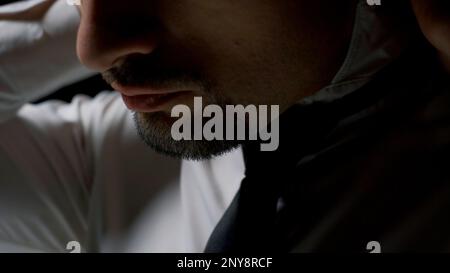 Primo piano di un uomo vestito con camicia bianca e cravatta scura. Riprese in stock. Le mani maschili stringono la cravatta intorno al collo Foto Stock