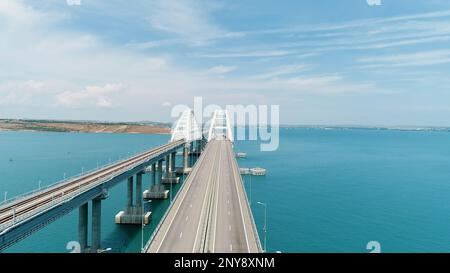 Veduta aerea mozzafiato del mare turchese e un lungo ponte bianco a forma di arco. Scatto. Trasporto percorrendo il ponte che attraversa il bl Foto Stock