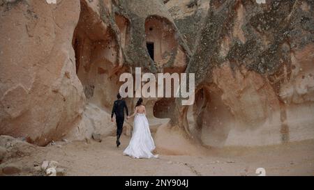 Bella giovane coppia sullo sfondo delle cime delle montagne in Cappadocia, Turchia. Azione. Azione. Amore romantico di coppia uomo e donna in Cappadoc Foto Stock