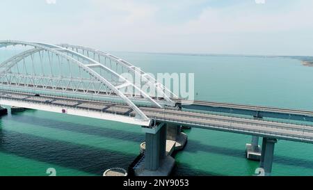 Veduta aerea mozzafiato del mare turchese e un lungo ponte bianco a forma di arco. Scatto. Trasporto percorrendo il ponte che attraversa il bl Foto Stock