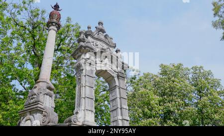 Antico arco monumento con alberi verdi. Azione. Vecchio edificio bianco con archi e motivi di stile orientale. Arco antico come parte del parco del palazzo in sume Foto Stock